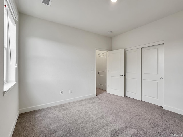unfurnished bedroom with baseboards, visible vents, a closet, and carpet floors