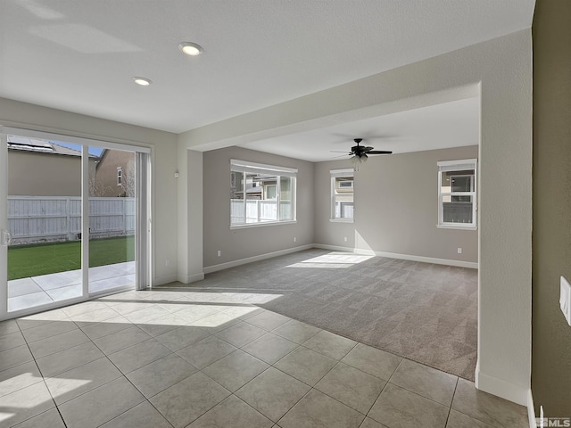 unfurnished room featuring tile patterned flooring, carpet, baseboards, and ceiling fan
