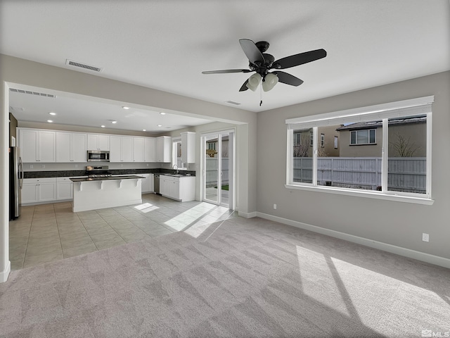 kitchen with dark countertops, light carpet, appliances with stainless steel finishes, and visible vents