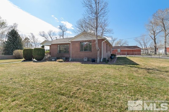 rear view of property featuring brick siding, fence, and a yard