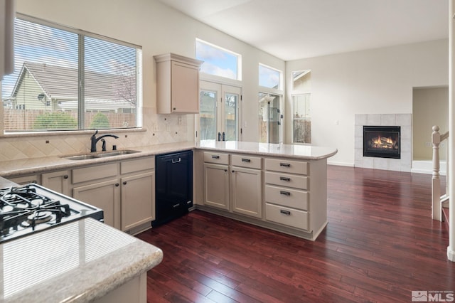 kitchen featuring black dishwasher, dark wood-style floors, a sink, and a peninsula