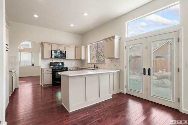 kitchen with french doors, dark wood-style flooring, backsplash, a peninsula, and black appliances