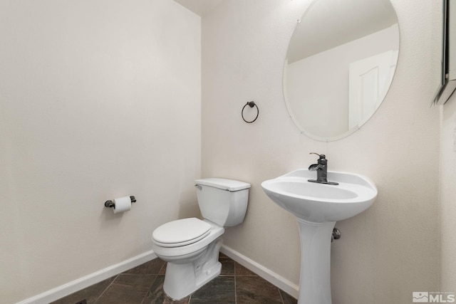 half bath with toilet, tile patterned flooring, and baseboards
