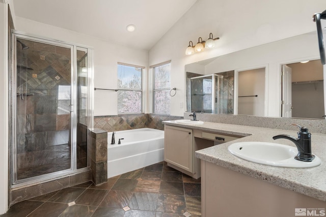 bathroom featuring a sink, a stall shower, lofted ceiling, and a garden tub