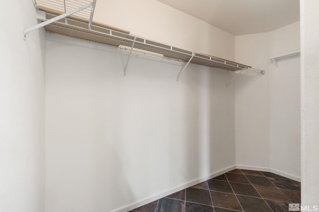 walk in closet with dark tile patterned flooring