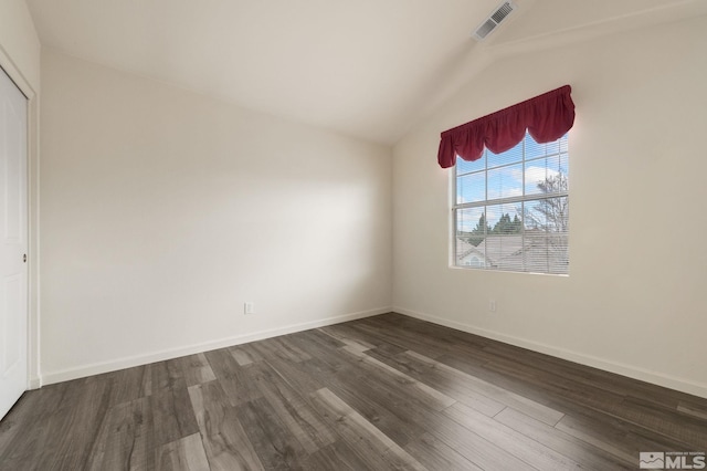 unfurnished bedroom with baseboards, dark wood-style floors, lofted ceiling, and visible vents