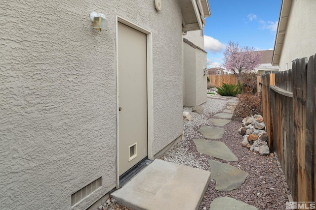 view of side of home featuring stucco siding and fence