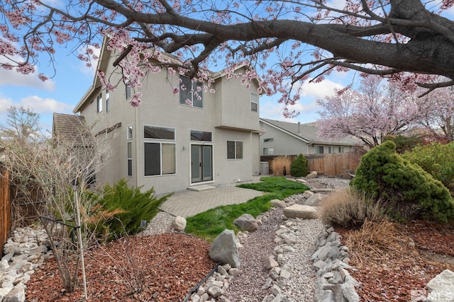rear view of property featuring stucco siding, fence, and a patio