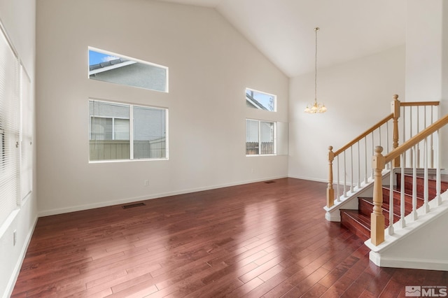 unfurnished living room featuring high vaulted ceiling, visible vents, a chandelier, baseboards, and wood-type flooring