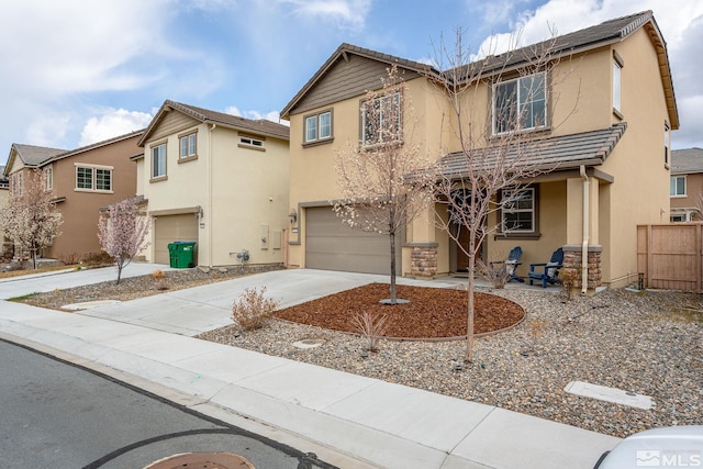 traditional home with fence, stucco siding, an attached garage, and concrete driveway