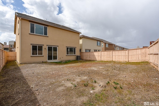 rear view of house featuring a fenced backyard, stucco siding, and central AC unit