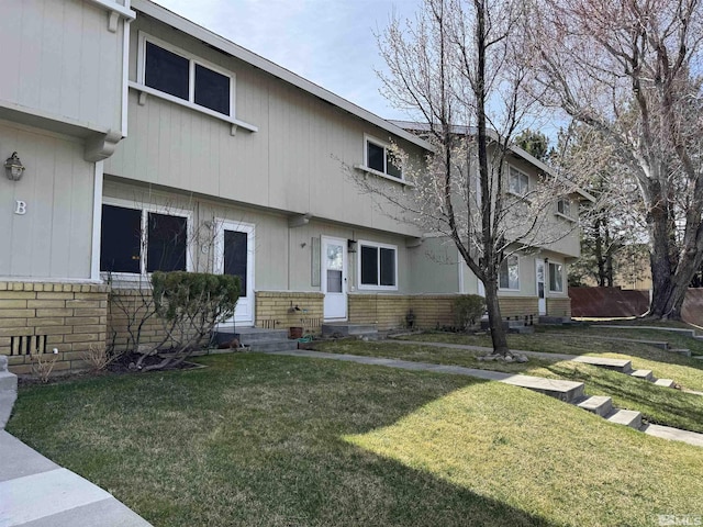 view of property featuring a front lawn and brick siding