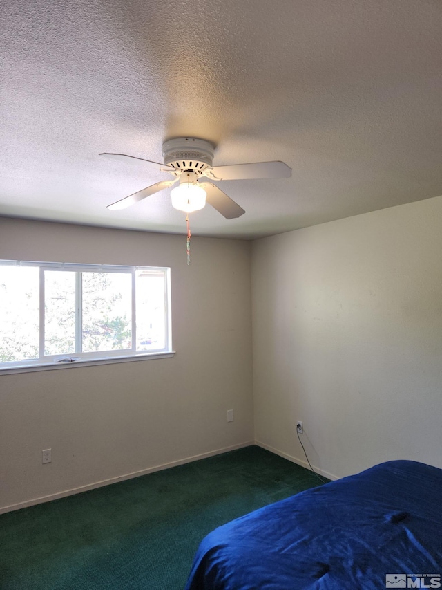 unfurnished bedroom with dark carpet, ceiling fan, baseboards, and a textured ceiling