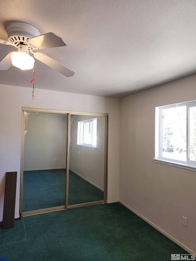 unfurnished bedroom featuring a textured ceiling, a closet, carpet flooring, and ceiling fan