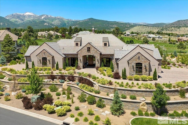 view of front of house featuring stone siding, a mountain view, and a tile roof