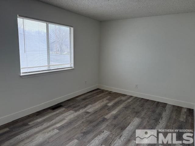 unfurnished room featuring a textured ceiling, wood finished floors, and baseboards