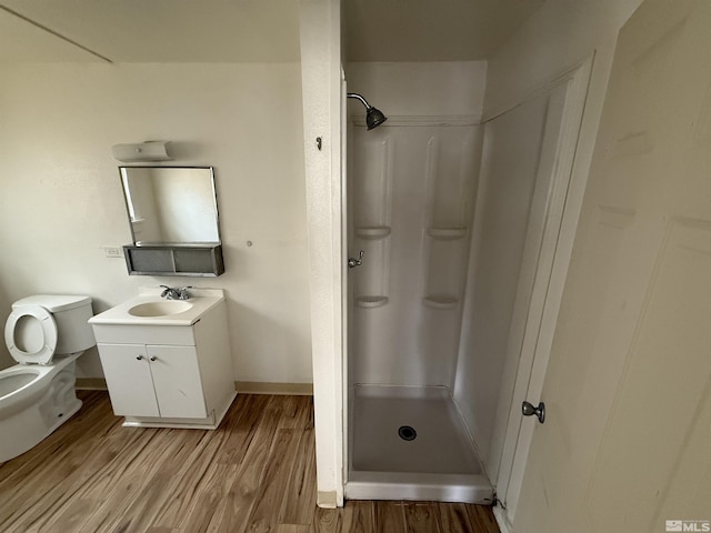 bathroom with a shower stall, wood finished floors, vanity, and toilet