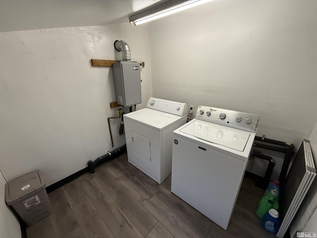 clothes washing area with dark wood-style floors, laundry area, water heater, and washer and clothes dryer