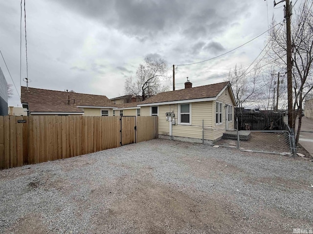 exterior space featuring a chimney, gravel driveway, fence, and a gate