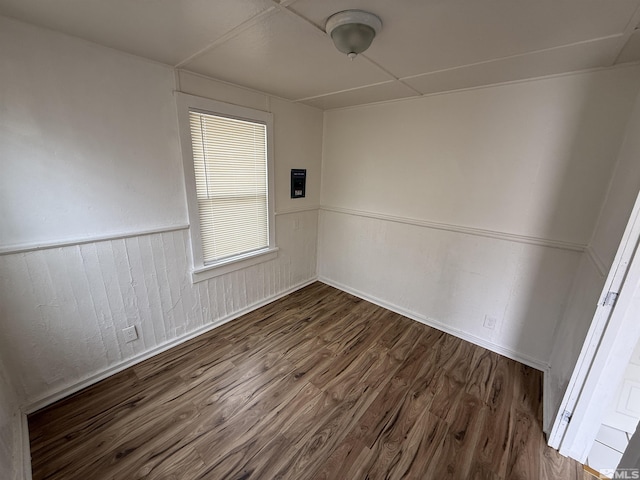 unfurnished room with a wainscoted wall and wood finished floors
