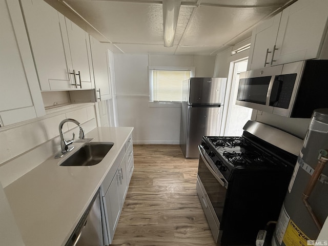 kitchen featuring stainless steel appliances, light wood-style flooring, white cabinetry, and a sink