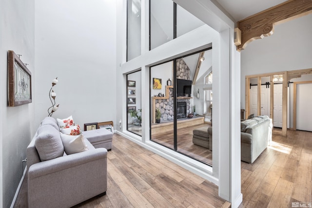 living area with wood-type flooring, a high ceiling, and a fireplace