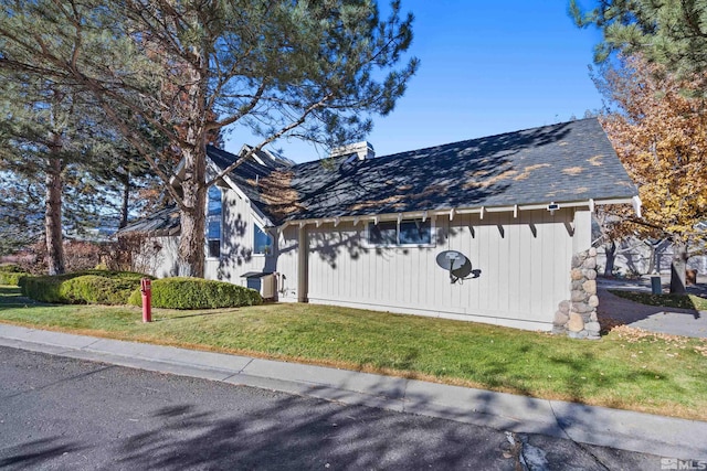 view of side of property with a yard and a shingled roof