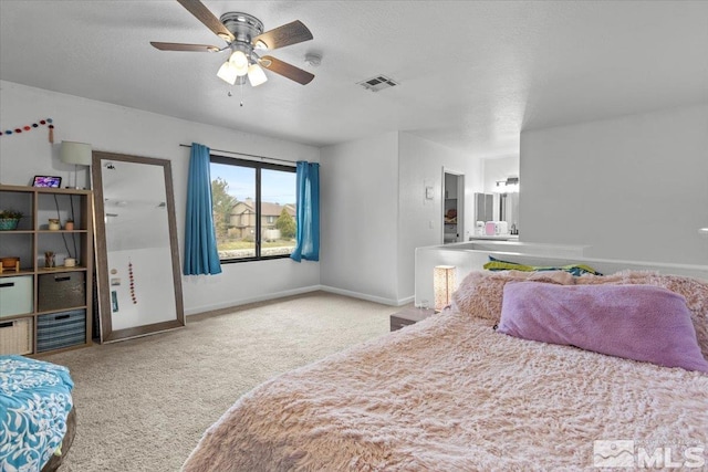 carpeted bedroom with a textured ceiling, baseboards, a ceiling fan, and visible vents