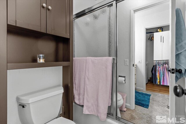 bathroom featuring toilet and a shower stall
