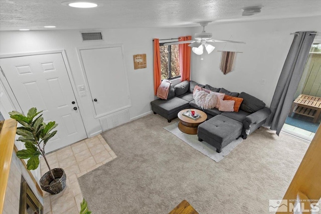 carpeted living room with a textured ceiling, a ceiling fan, and visible vents