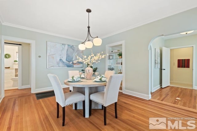 dining room featuring an inviting chandelier, baseboards, crown molding, and wood finished floors