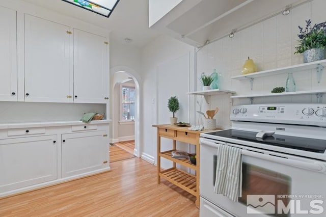 kitchen featuring light wood-style floors, white range with electric cooktop, arched walkways, white cabinets, and light countertops