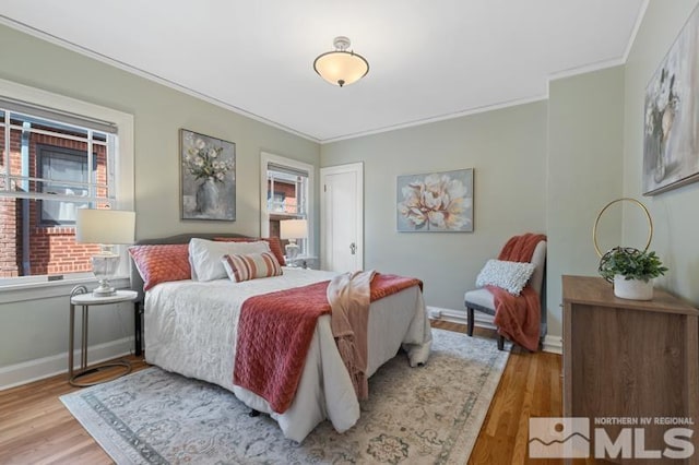 bedroom with crown molding, wood finished floors, and baseboards