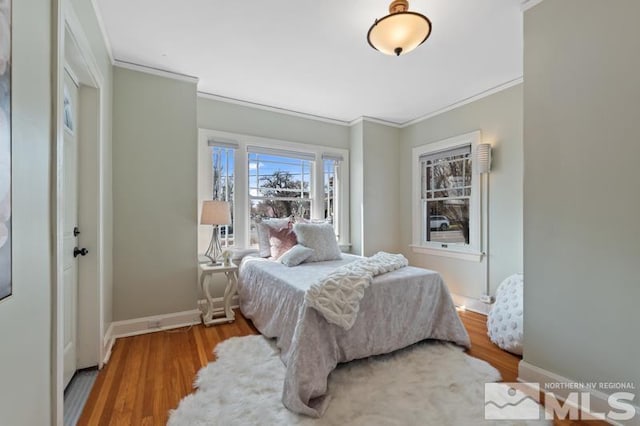 bedroom featuring baseboards, crown molding, and wood finished floors
