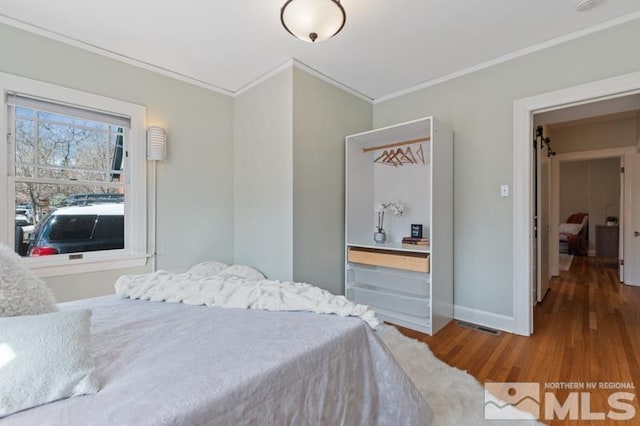 bedroom featuring crown molding, wood finished floors, and baseboards