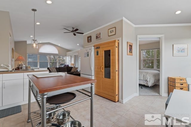 kitchen with vaulted ceiling, ornamental molding, light tile patterned floors, white cabinets, and ceiling fan