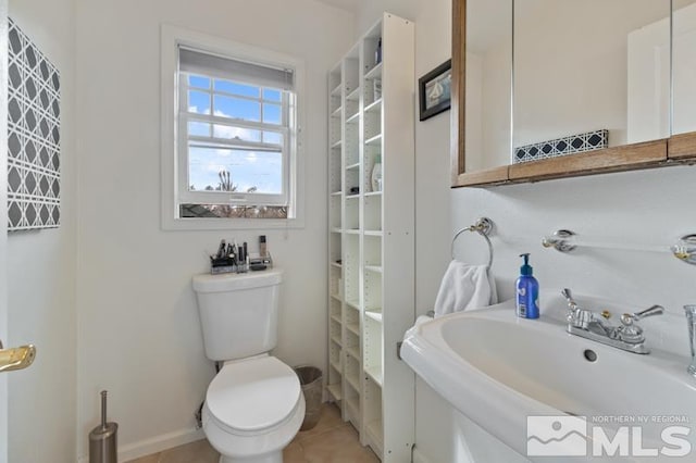 bathroom with tile patterned flooring, baseboards, a sink, and toilet