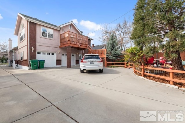 exterior space featuring brick siding, an attached garage, fence, and concrete driveway