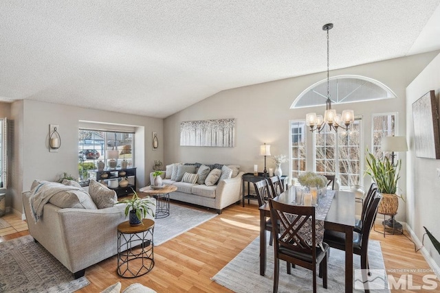 dining room with light wood-type flooring, an inviting chandelier, vaulted ceiling, and a textured ceiling