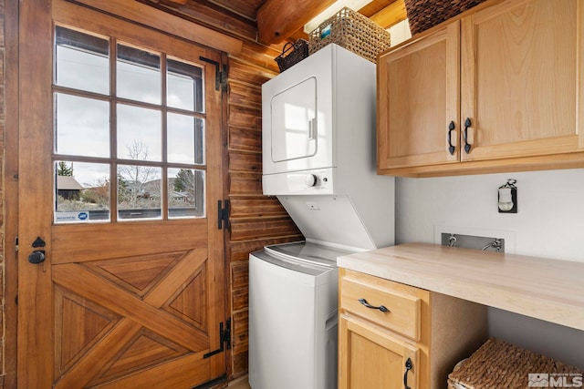 laundry area featuring stacked washing maching and dryer and cabinet space