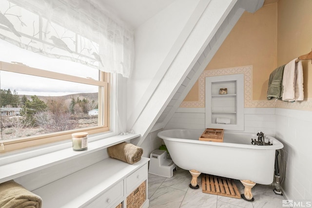 full bathroom with a freestanding tub, wainscoting, and marble finish floor