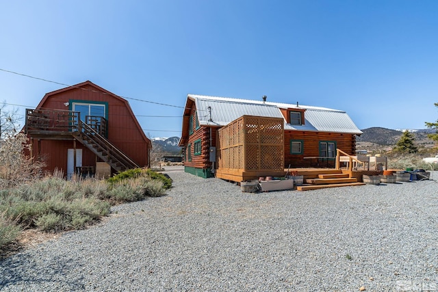 exterior space featuring a deck with mountain view, a gambrel roof, metal roof, and log exterior
