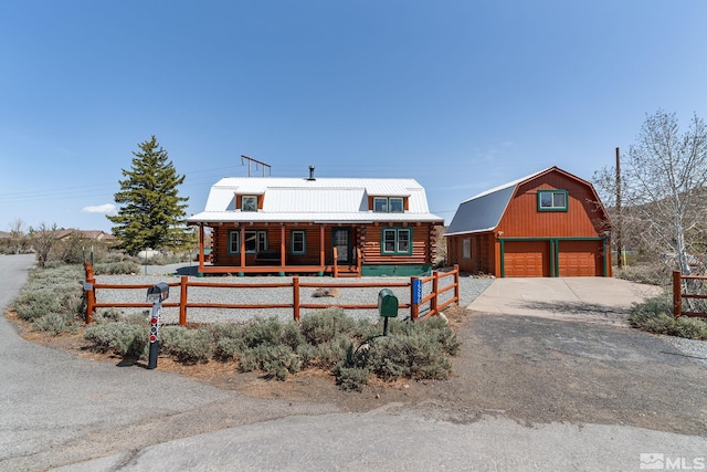 log-style house with log exterior, a garage, fence, an outdoor structure, and a gambrel roof