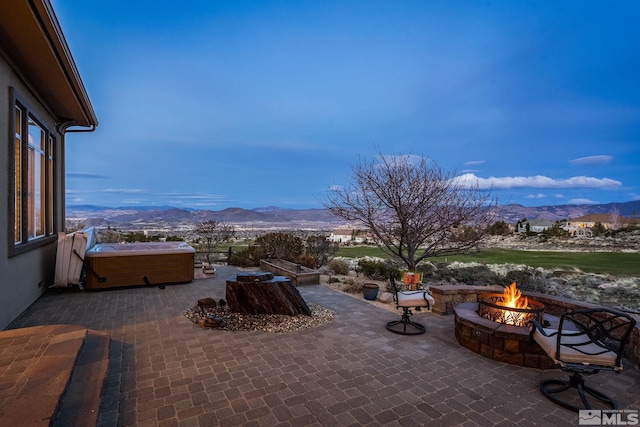 view of patio / terrace featuring a mountain view, a fire pit, and a hot tub