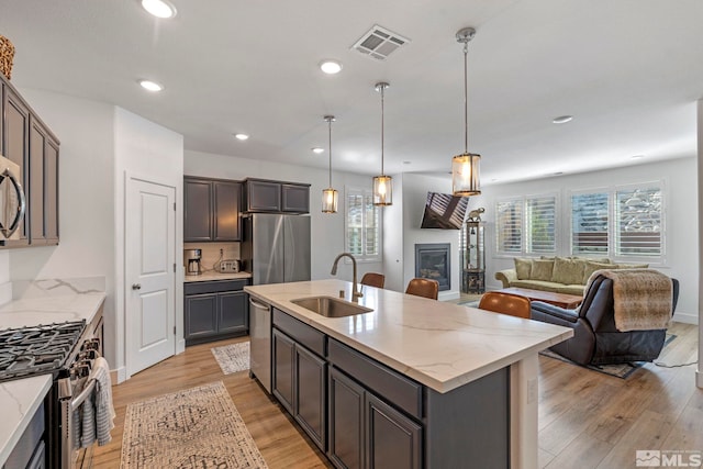 kitchen with open floor plan, light wood-style floors, visible vents, appliances with stainless steel finishes, and a sink