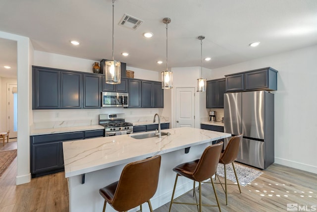 kitchen with light wood-type flooring, visible vents, light stone counters, a sink, and stainless steel appliances
