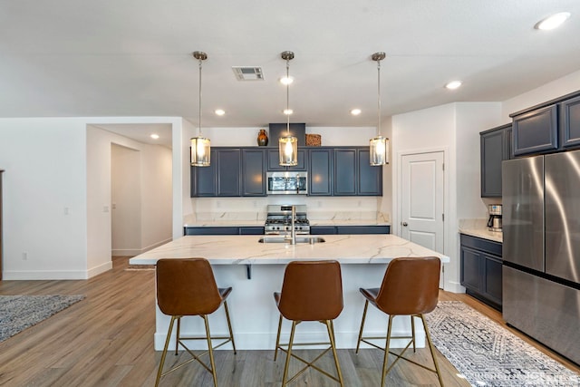 kitchen featuring light stone countertops, light wood-style floors, visible vents, a breakfast bar area, and appliances with stainless steel finishes