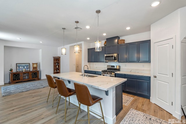 kitchen with visible vents, a sink, light wood-type flooring, appliances with stainless steel finishes, and a breakfast bar area