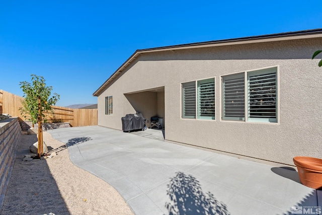 rear view of house with a patio area, stucco siding, and a fenced backyard