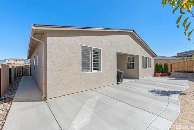 back of property with a patio, stucco siding, and a fenced backyard